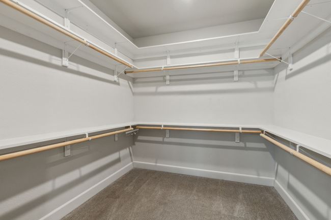 Walk in closet featuring dark colored carpet | Image 15