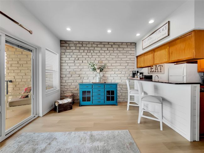Kitchen featuring freestanding refrigerator, light wood-style floors, dark countertops, a sink, and recessed lighting | Image 10