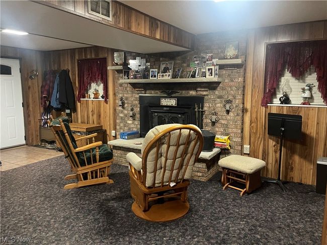 Sitting room featuring brick wall, wooden walls, light carpet, and a brick fireplace | Image 21