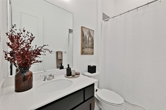 Bathroom featuring toilet, vanity, and curtained shower | Image 23