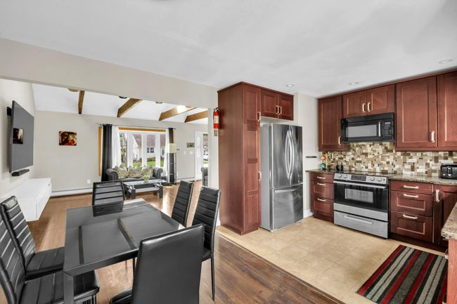 Kitchen with light stone counters, open floor plan, stainless steel appliances, backsplash, and beam ceiling | Image 6