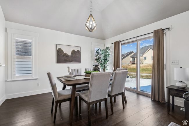 Dining space with a healthy amount of sunlight, a chandelier, lofted ceiling, and dark hardwood / wood-style floors. plantation shutters. | Image 9
