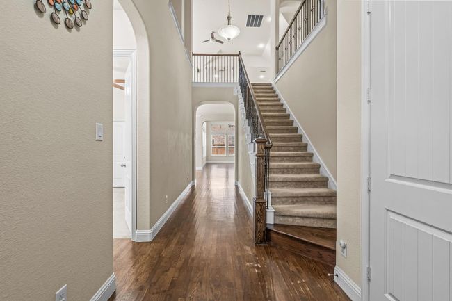 Foyer with arched walkways, wood-type flooring, stairs, a textured wall, and baseboards | Image 5