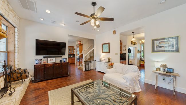 Living area with wood-type flooring, a ceiling fan, stairway, and visible vents | Image 16