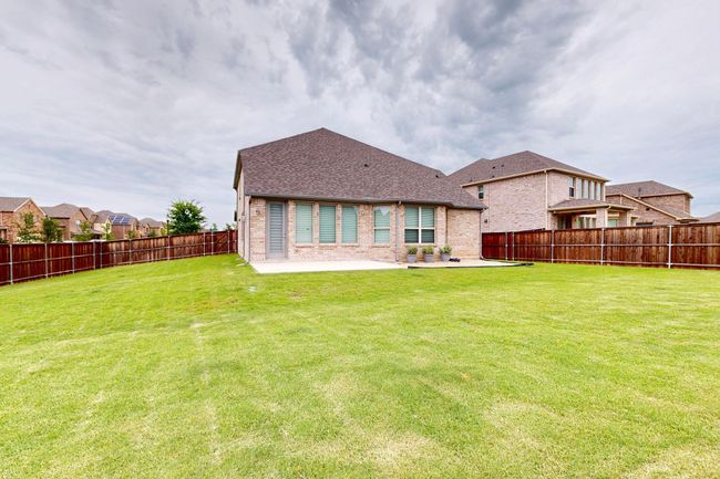Rear view of house with brick siding, a patio area, a fenced backyard, and a shingled roof | Image 35