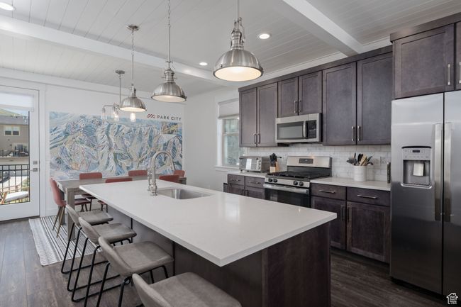 Kitchen featuring appliances with stainless steel finishes, a sink, dark wood finished floors, backsplash, and wood ceiling with exposed beams | Image 8