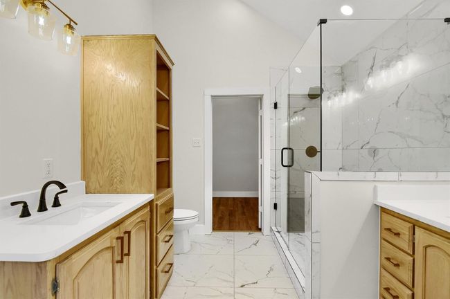 Bathroom featuring vanity, marble look tile flooring, a marble finish shower, and toilet | Image 15