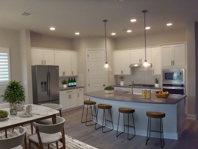 Kitchen featuring appliances with stainless steel finishes, light wood-type flooring, backsplash, a breakfast bar area, and dark countertops | Image 12