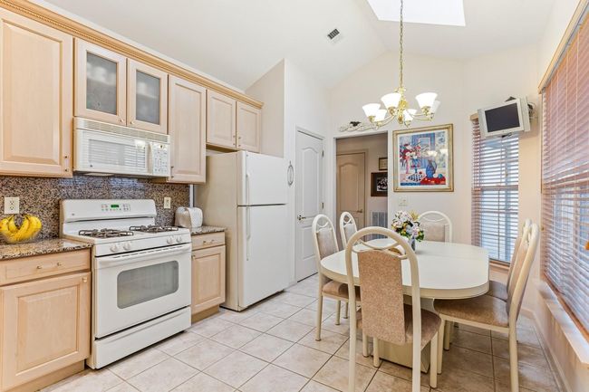 Kitchen featuring white appliances, an inviting chandelier, light brown cabinetry, backsplash, and visible vents | Image 30