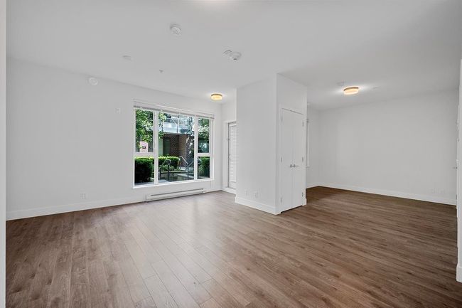 Empty room featuring wood finished floors, a baseboard radiator, and a smoke detector | Image 19