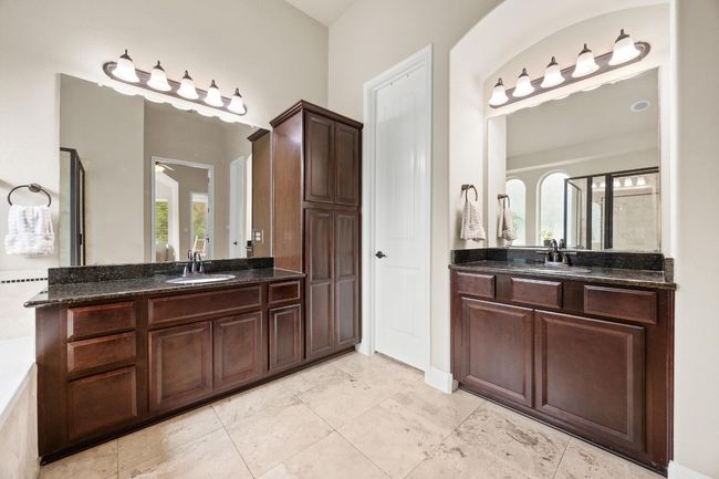 Primary bathroom with two vanity sinks with quartz counters and storage | Image 19