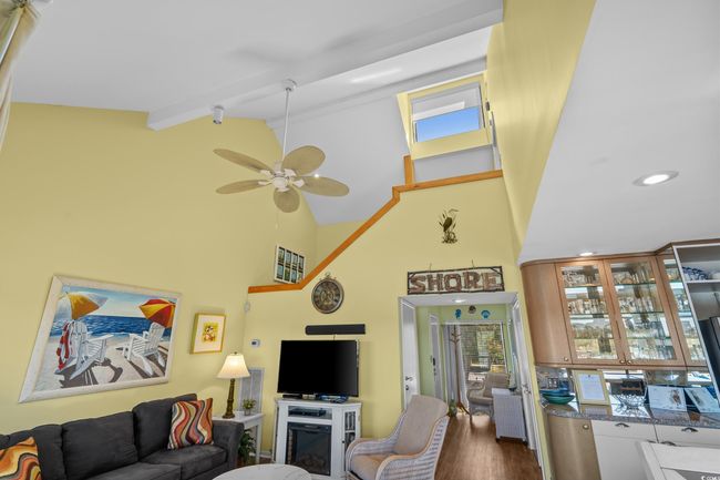 Living area featuring recessed lighting, high vaulted ceiling, beam ceiling, a ceiling fan, and wood finished floors | Image 13