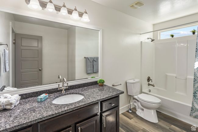 Full bath with vanity, shower / bath combination with curtain, toilet, visible vents, and wood finished floors | Image 23