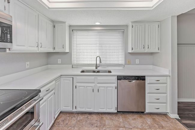 Kitchen with appliances with stainless steel finishes, a sink, white cabinetry, and light countertops | Image 9