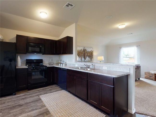 Kitchen featuring dark brown cabinets, light hardwood / wood-style flooring, black appliances, kitchen peninsula, and sink | Image 8