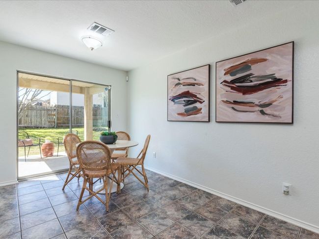 The sunny dining area is nestled alongside sliding glass doors leading to a covered back porch, ideal for grilling and dining outdoors. | Image 15