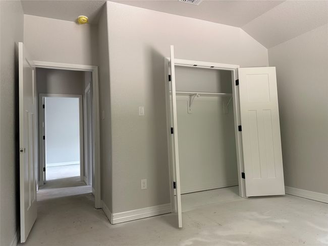Unfurnished bedroom featuring concrete floors, a closet, baseboards, and lofted ceiling | Image 18