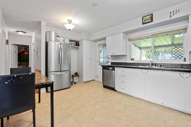 Kitchen with dark countertops, appliances with stainless steel finishes, a sink, and a healthy amount of sunlight | Image 6