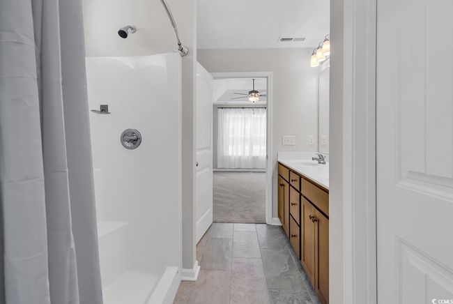 Bathroom with ceiling fan, a shower, vanity, and baseboards | Image 21