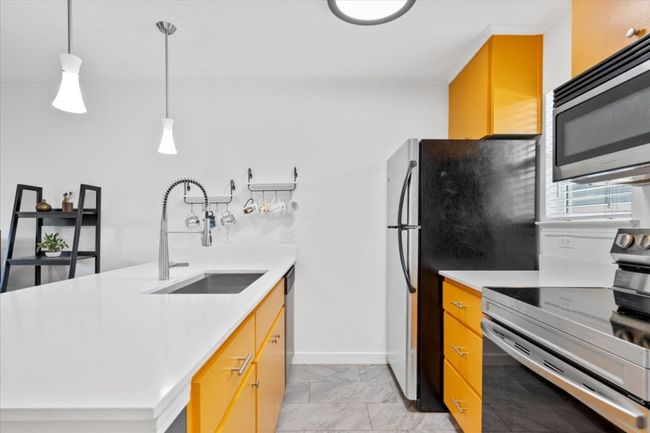 Kitchen with appliances with stainless steel finishes, light countertops, and decorative light fixtures | Image 10