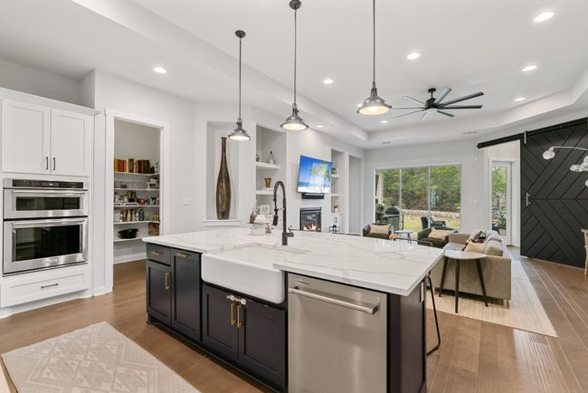 Kitchen with stainless steel appliances, open floor plan, a ceiling fan, wood finished floors, and white cabinets | Image 12