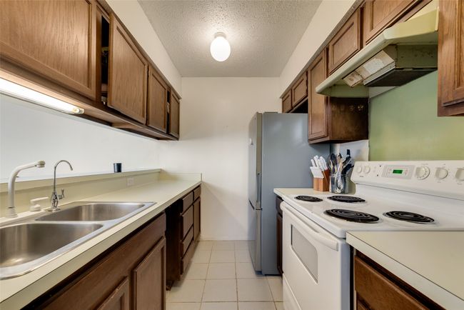 Kitchen featuring light tile patterned floors, a textured ceiling, white electric stove, and sink | Image 5