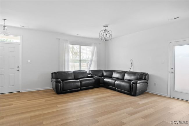 Living room featuring visible vents, light wood-style flooring, and a chandelier | Image 7
