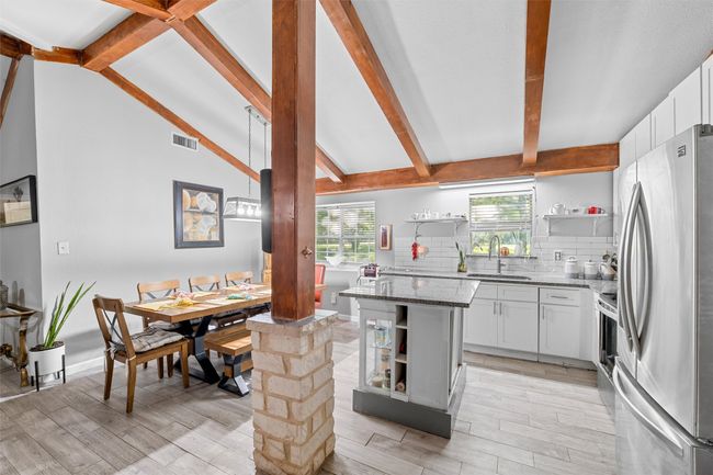 Kitchen with open shelves, visible vents, dark stone countertops, a sink, and stainless steel appliances | Image 14