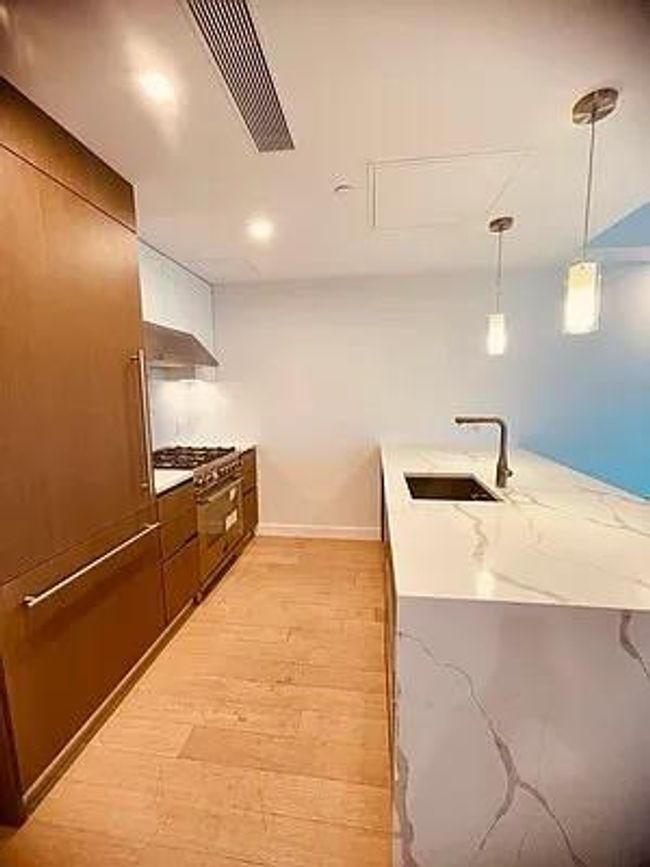 Kitchen with stainless steel range, a sink, a peninsula, light wood-type flooring, and pendant lighting | Image 19