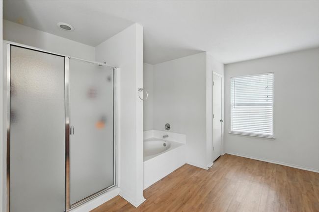 Bathroom with a garden tub, wood finished floors, a shower stall, and baseboards | Image 12