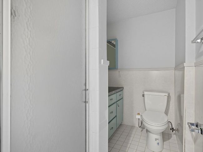 Bathroom with light tile patterned floors, vanity, a textured ceiling, wainscoting, and a stall shower | Image 21