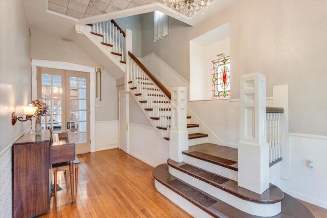 Entry with original floors, grand staircase, stained glass window, original french doors | Image 5