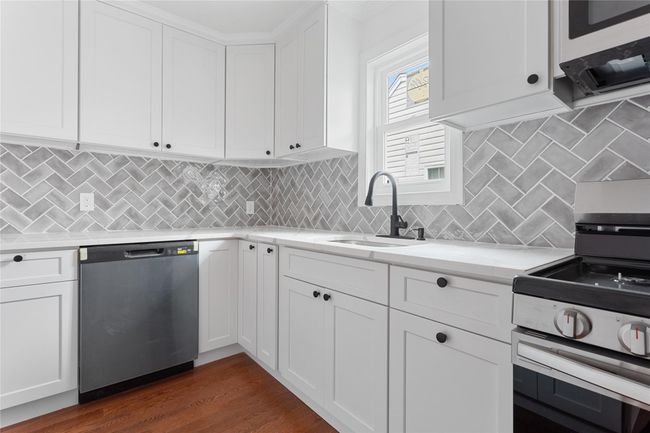 Kitchen with appliances with stainless steel finishes, a sink, and white cabinets | Image 13