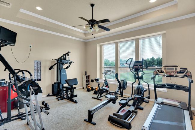 Workout area featuring a tray ceiling, a ceiling fan, carpet flooring, baseboards, and ornamental molding | Image 13
