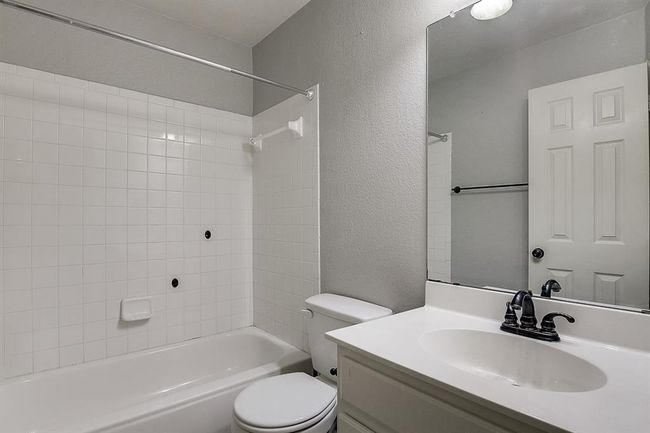 Full bathroom with toilet, bathtub / shower combination, vanity, and a textured wall | Image 14