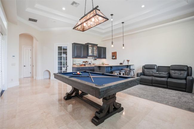 Designed for entertaining, the game room features a full wet bar with bar seating, custom cabinetry, and plenty of space for lounging, games, and relaxed gatherings. | Image 15