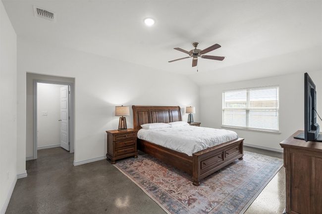 Bedroom featuring baseboards, a ceiling fan, finished concrete floors, and visible vents | Image 10