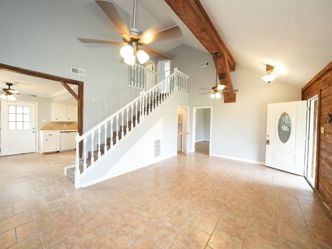 Unfurnished living room featuring ceiling fan, stairs, high vaulted ceiling, and beam ceiling | Image 12