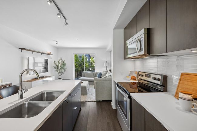 Kitchen featuring appliances with stainless steel finishes, a sink, open floor plan, and light countertops | Image 8