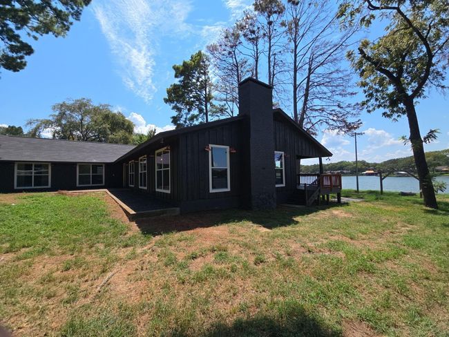 View of side of property featuring board and batten siding, a lawn, and a chimney | Image 4