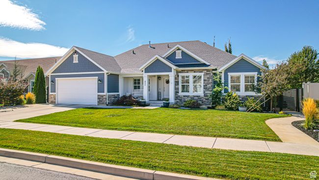 View of front of property with fence, an attached garage, stone siding, and concrete driveway | Image 42