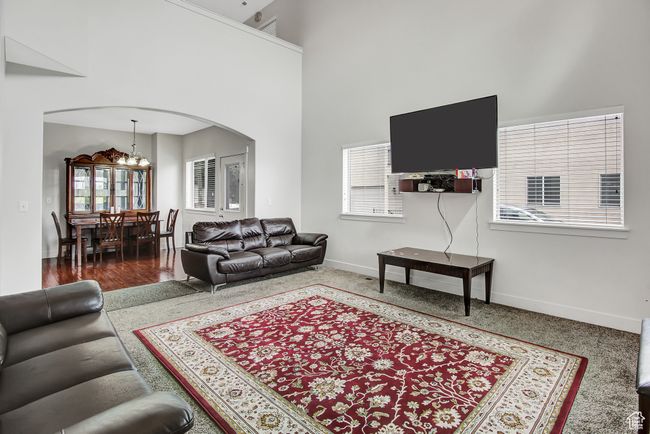 Carpeted living room featuring arched walkways, a chandelier, and a high ceiling | Image 7
