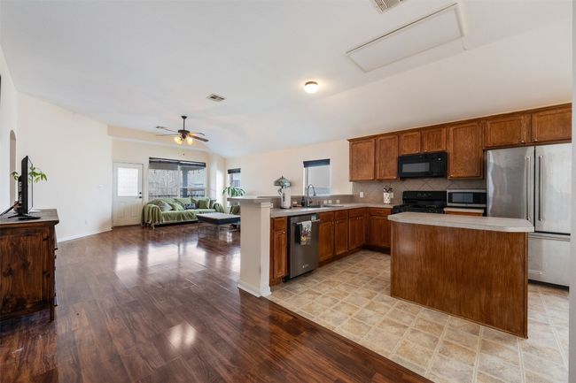 Kitchen with a ceiling fan, a sink, black appliances, light countertops, and open floor plan | Image 12