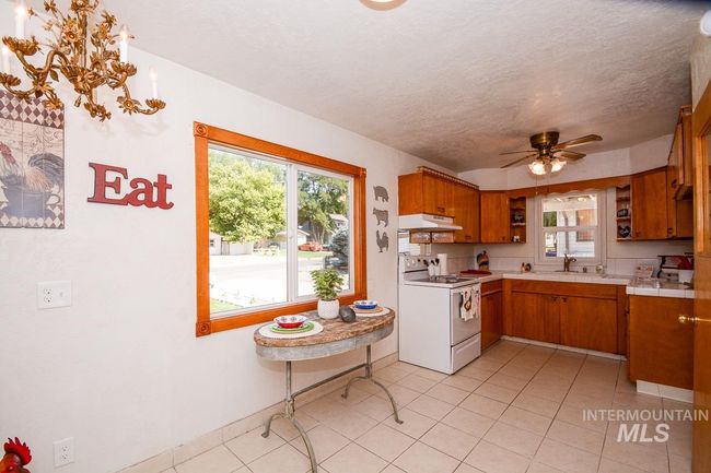 Kitchen featuring electric stove, brown cabinetry, under cabinet range hood, ceiling fan, and open shelves | Image 14