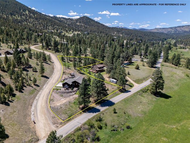 Aerial view of property and surrounding area with a forest, a mountainous background, and property parcel outlined | Image 56