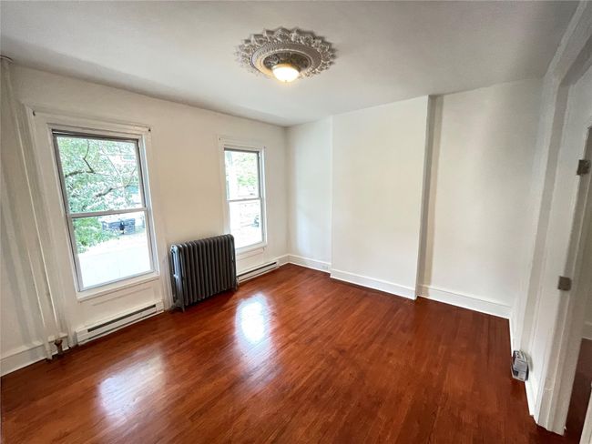 Unfurnished room with radiator heating unit, a baseboard radiator, and dark wood-style flooring | Image 5