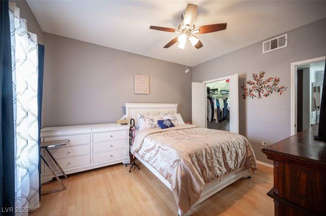 Bedroom with light wood-type flooring, a closet, a ceiling fan, visible vents, and a walk in closet | Image 18