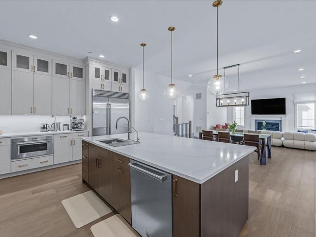 Kitchen featuring light wood finished floors, light countertops, a sink, and stainless steel appliances | Image 8