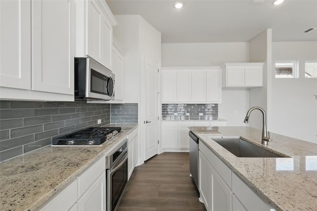 Kitchen featuring dark wood finished floors, recessed lighting, appliances with stainless steel finishes, white cabinetry, and a sink | Image 5
