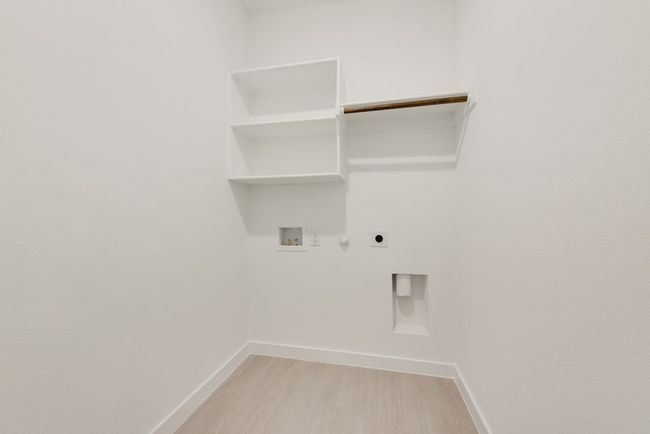 Laundry area featuring electric dryer hookup, gas dryer hookup, hookup for a washing machine, light wood finished floors, and baseboards | Image 16